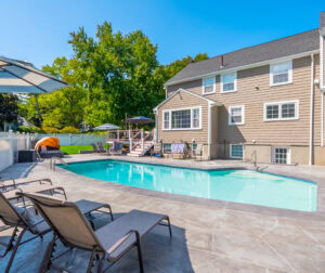 House in Dedham, MA with pool in backyard after pool renovation by Dex by Terra.