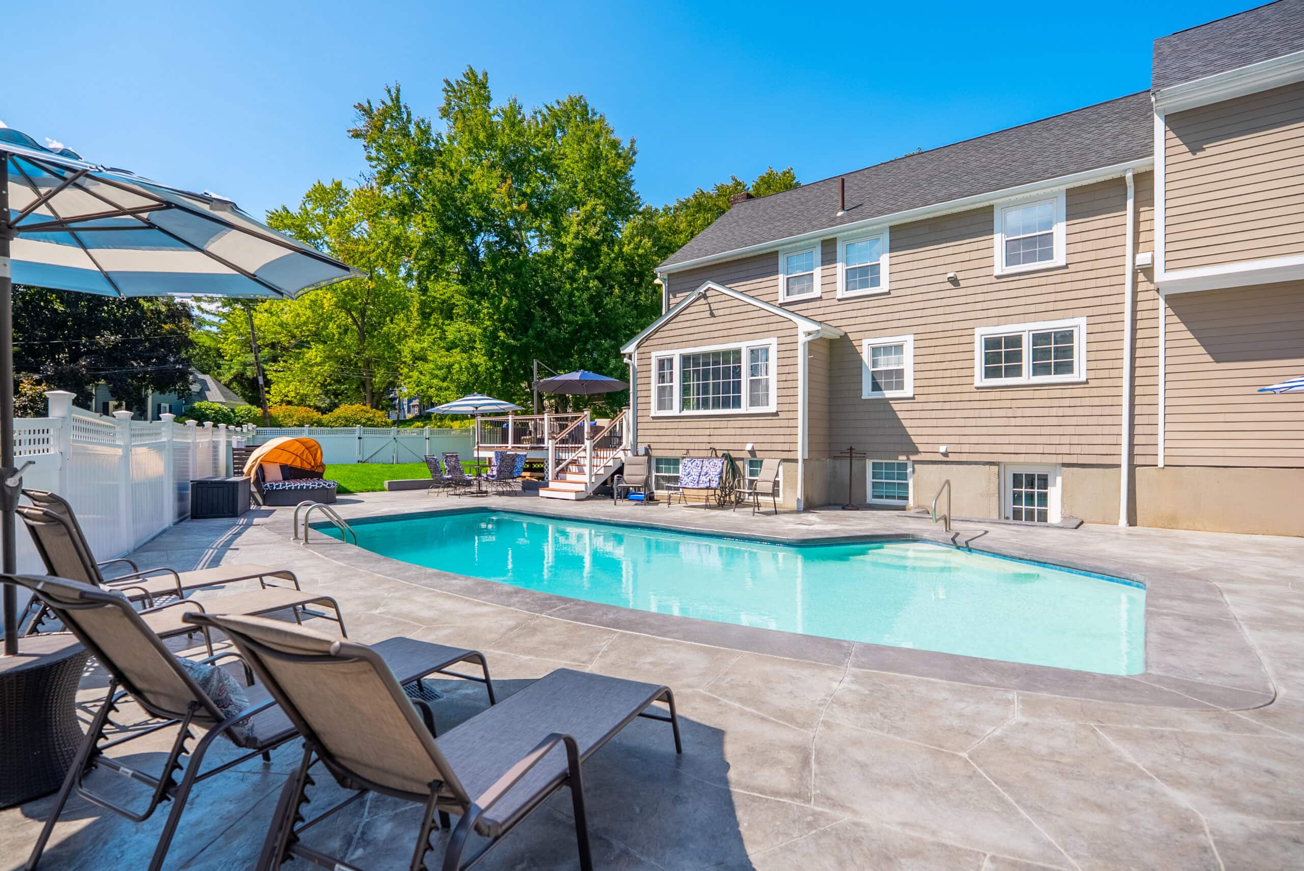 House in Dedham, MA with pool in backyard after pool renovation by Dex by Terra.