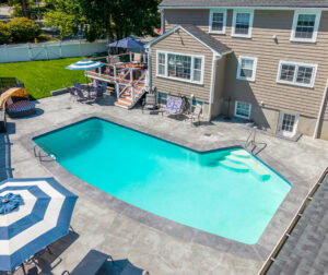 Drove view of house in Dedham, MA with pool in backyard after pool renovation by Dex by Terra.