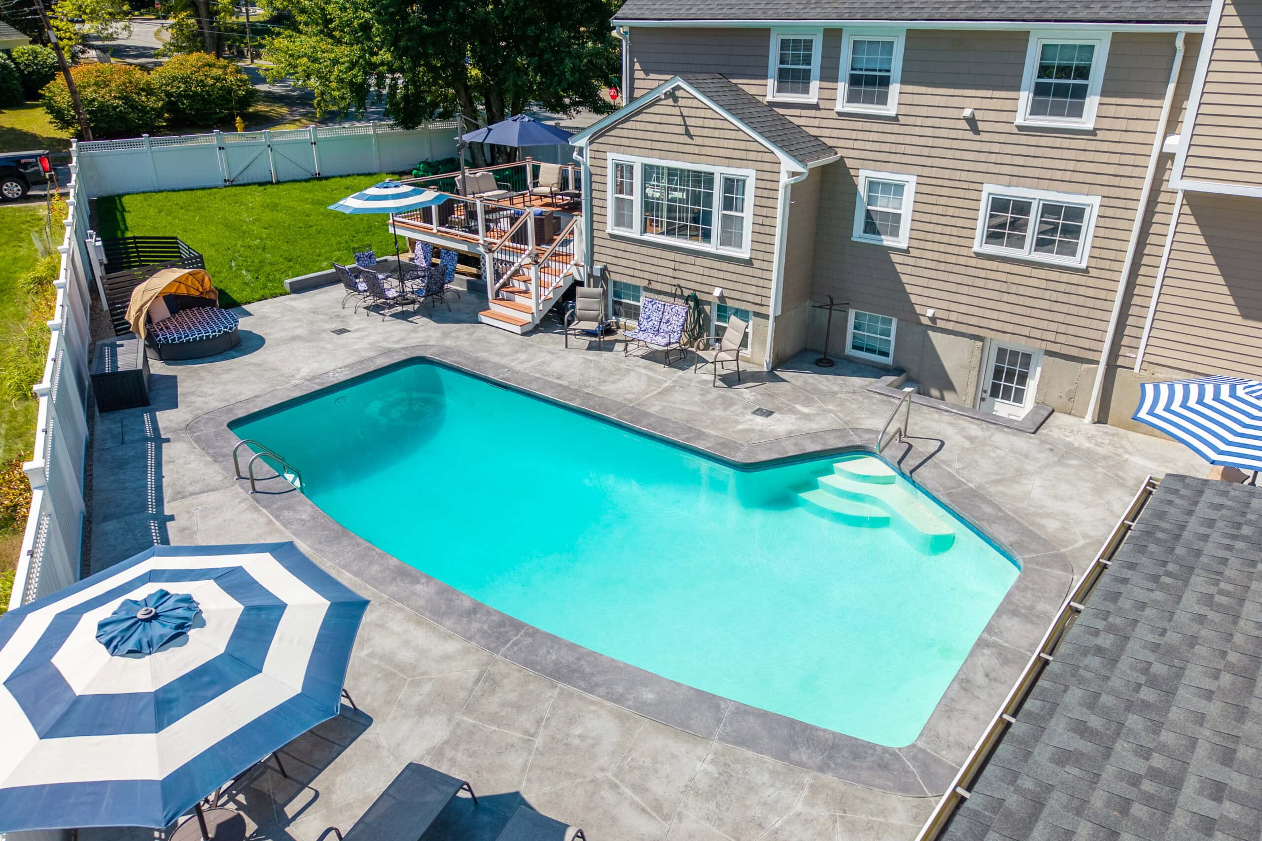 Drove view of house in Dedham, MA with pool in backyard after pool renovation by Dex by Terra.
