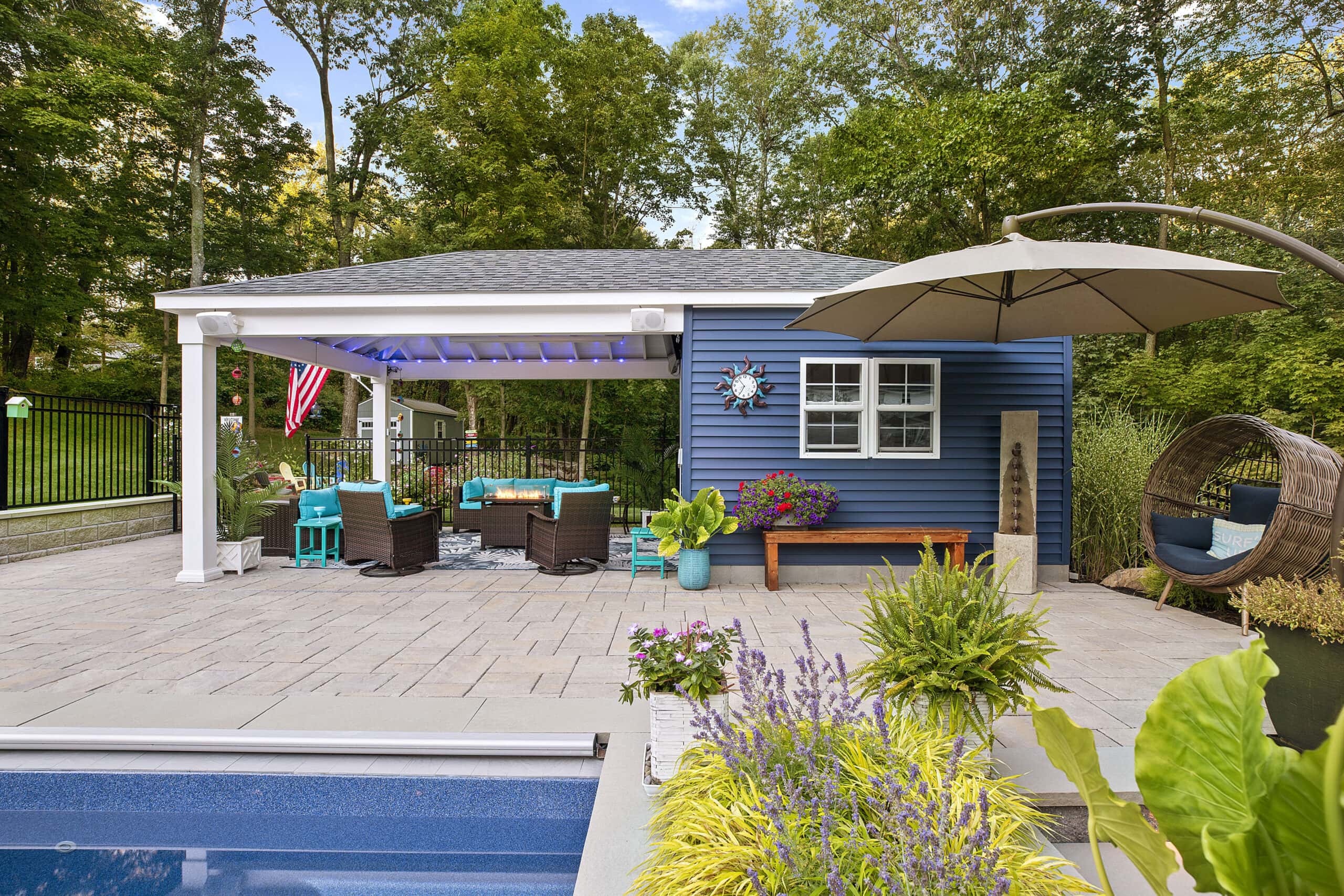 The pool house and pavilion with fire pit and seating. Dex by Terra landscape and hardscape project in Westminster, MA.