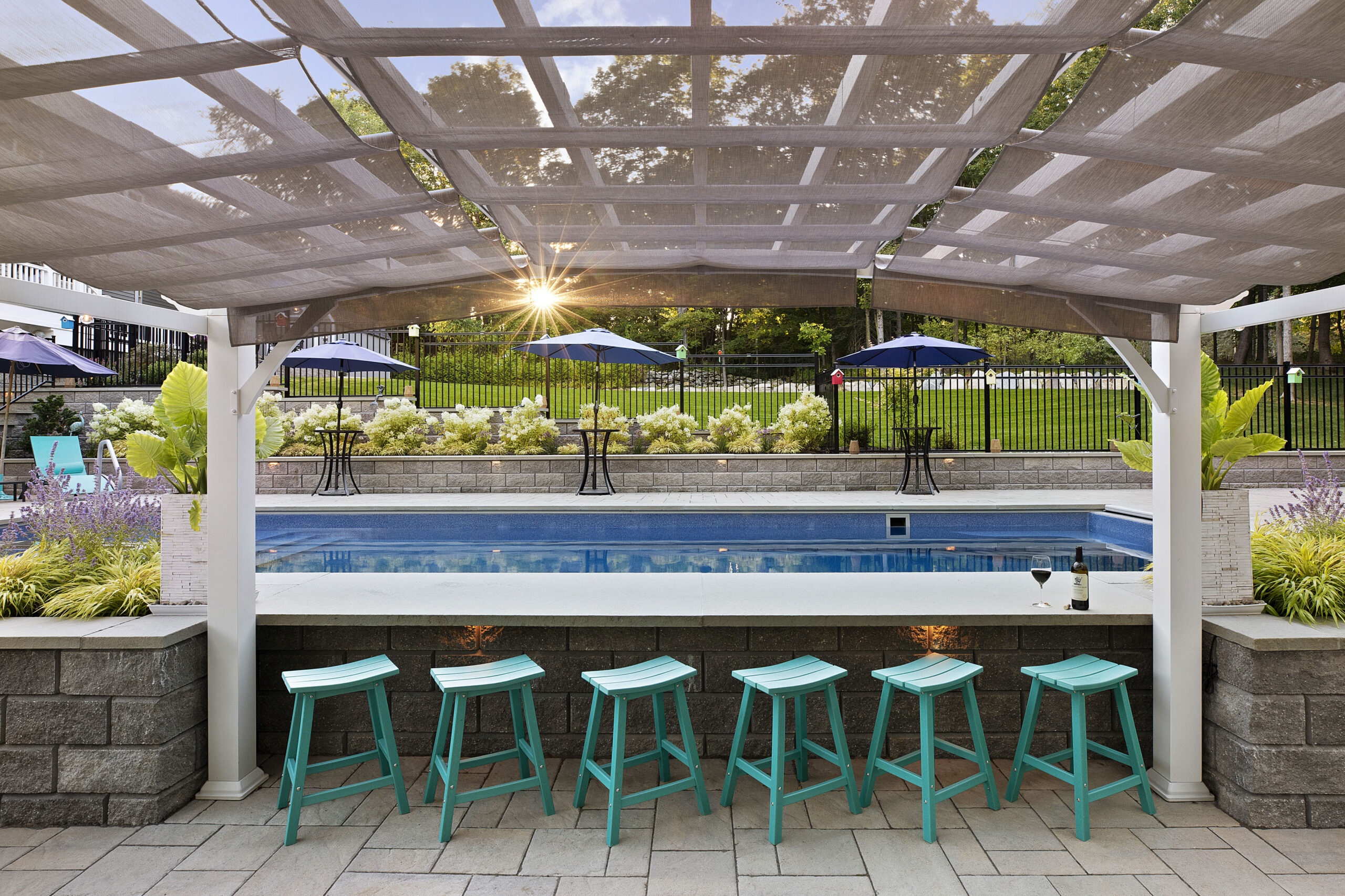 The poolside bar with sun setting in background. Dex by Terra landscape and hardscape project in Westminster, MA.