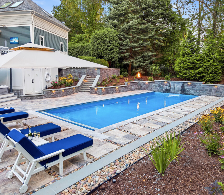 Drone view of pool deck, patio, and landscaping surrounding the pool. Dex by Terra Hardscaping and Landscaping project in Lincoln, MA.