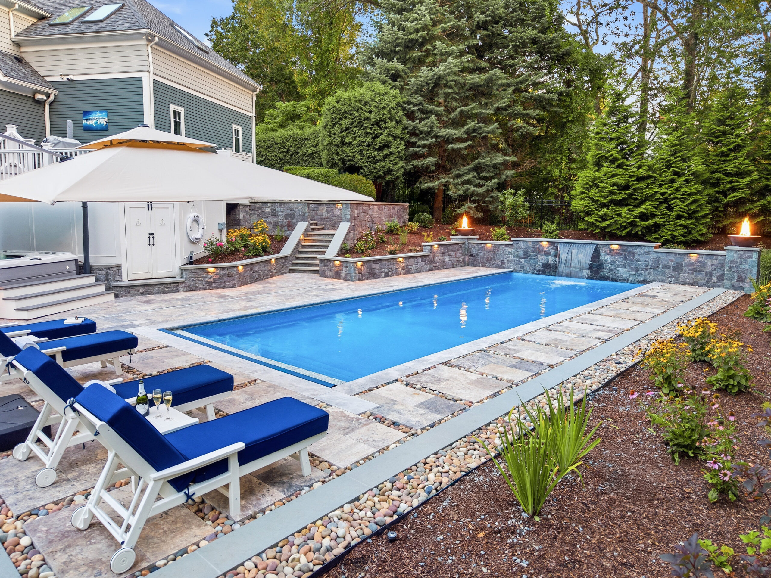 Drone view of pool deck, patio, and landscaping surrounding the pool. Dex by Terra Hardscaping and Landscaping project in Lincoln, MA.