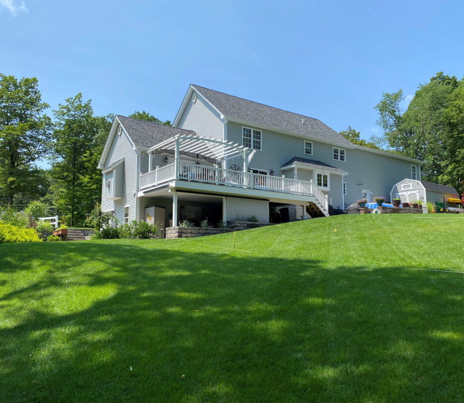 A view of the client's backyard looking toward their home before Dex by Terra's landscape and hardscape design build project in Westminster, Massachusetts.
