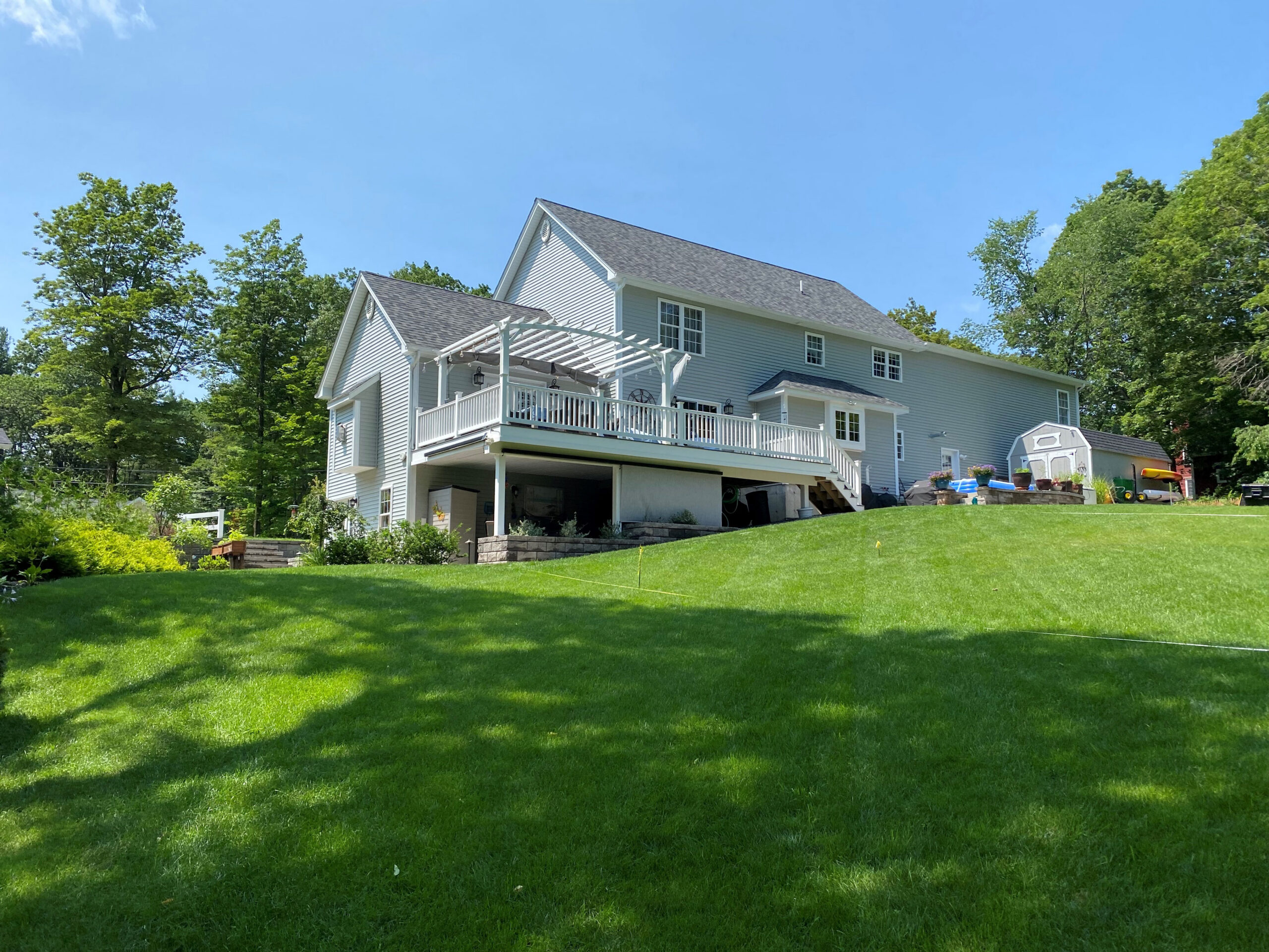 A view of the client's backyard looking toward their home before Dex by Terra's landscape and hardscape design build project in Westminster, Massachusetts.