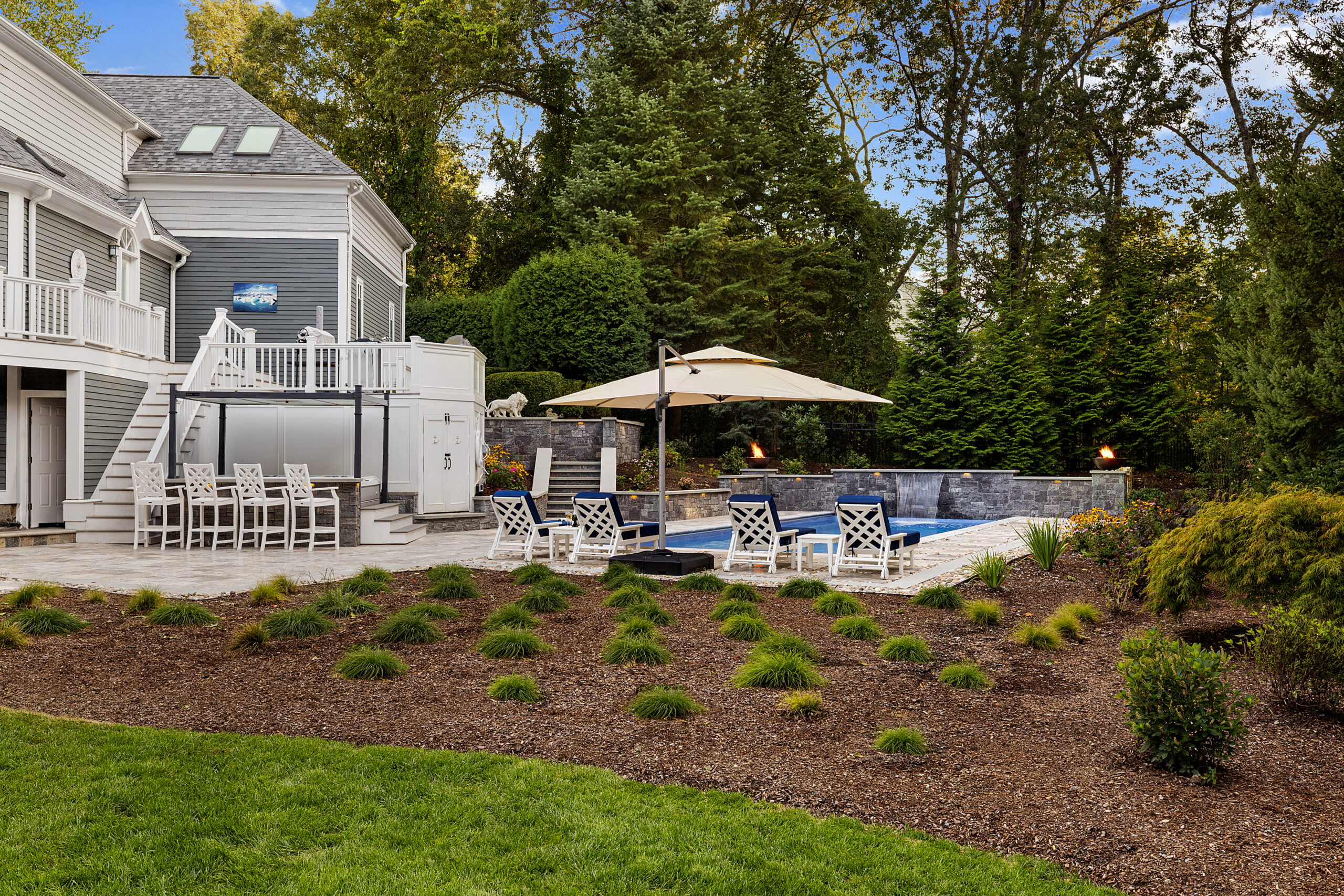 The hot tub and pool area with landscaping flowerbed in the foreground. Dex by Terra hardscape project in Lincoln, MA.
