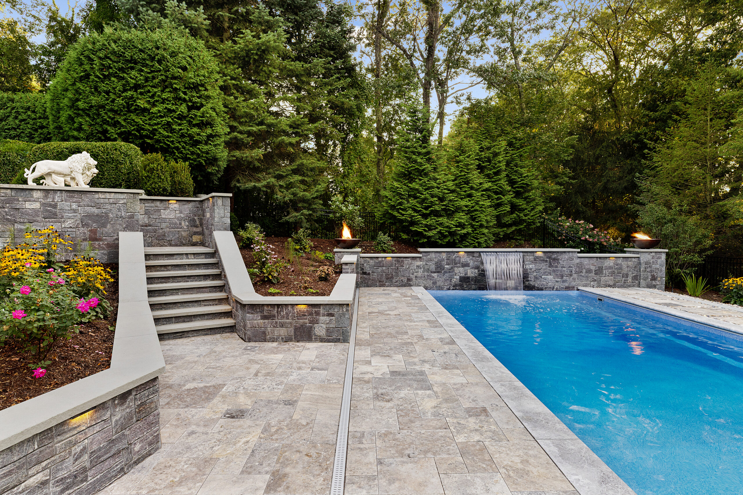 The stone stairs lead to the pool area with water and fire features. Dex by Terra hardscape project in Lincoln, MA.