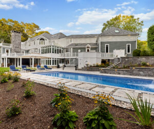 The pool area with the clients home in the background. Dex by Terra hardscape project in Lincoln, MA.