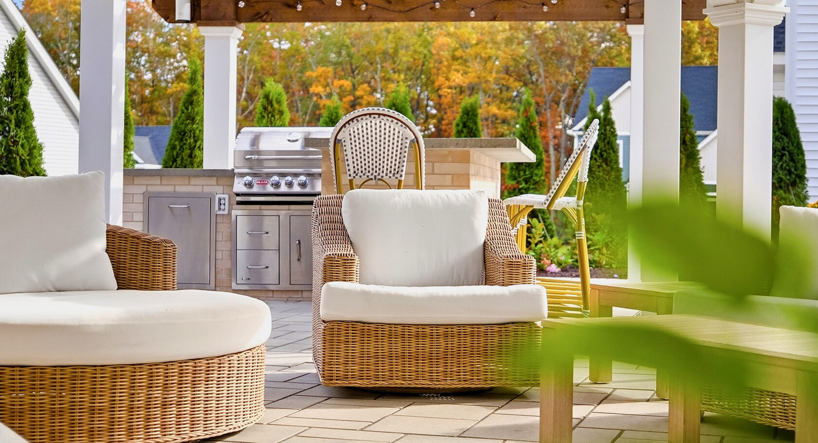Seating under the patio pavilion with outdoor Kitchen in the background. Outdoor living designed and built by Dex by Terra in North Attleboro, MA.