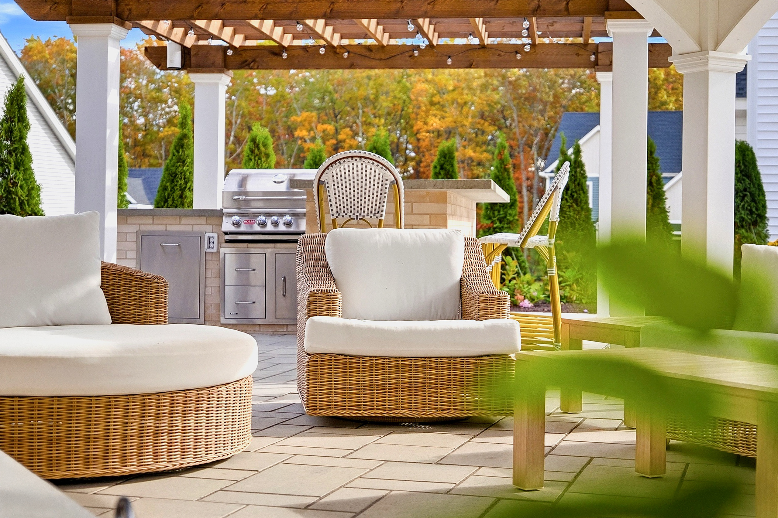 Seating under the patio pavilion with outdoor Kitchen in the background. Outdoor living designed and built by Dex by Terra in North Attleboro, MA.