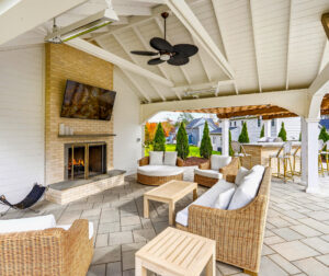 Seating under the patio pavilion with privacy wall and fireplace designed and built by Dex by Terra in North Attleborough, MA.