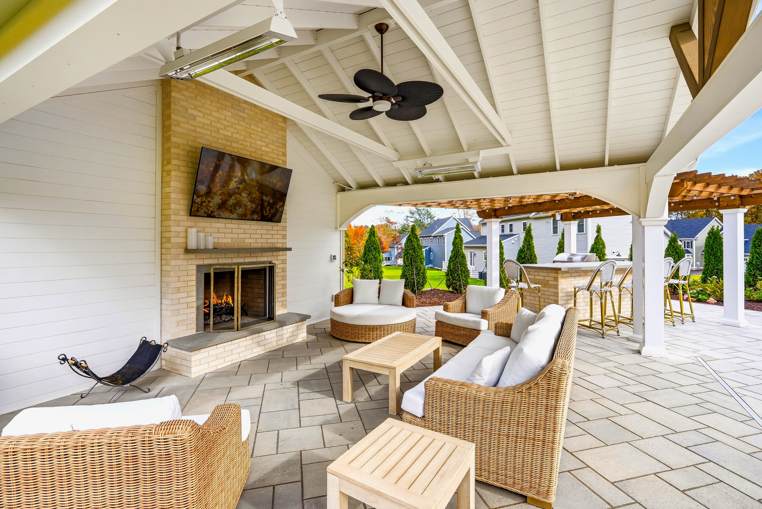Seating under the patio pavilion with privacy wall and fireplace designed and built by Dex by Terra in North Attleborough, MA.