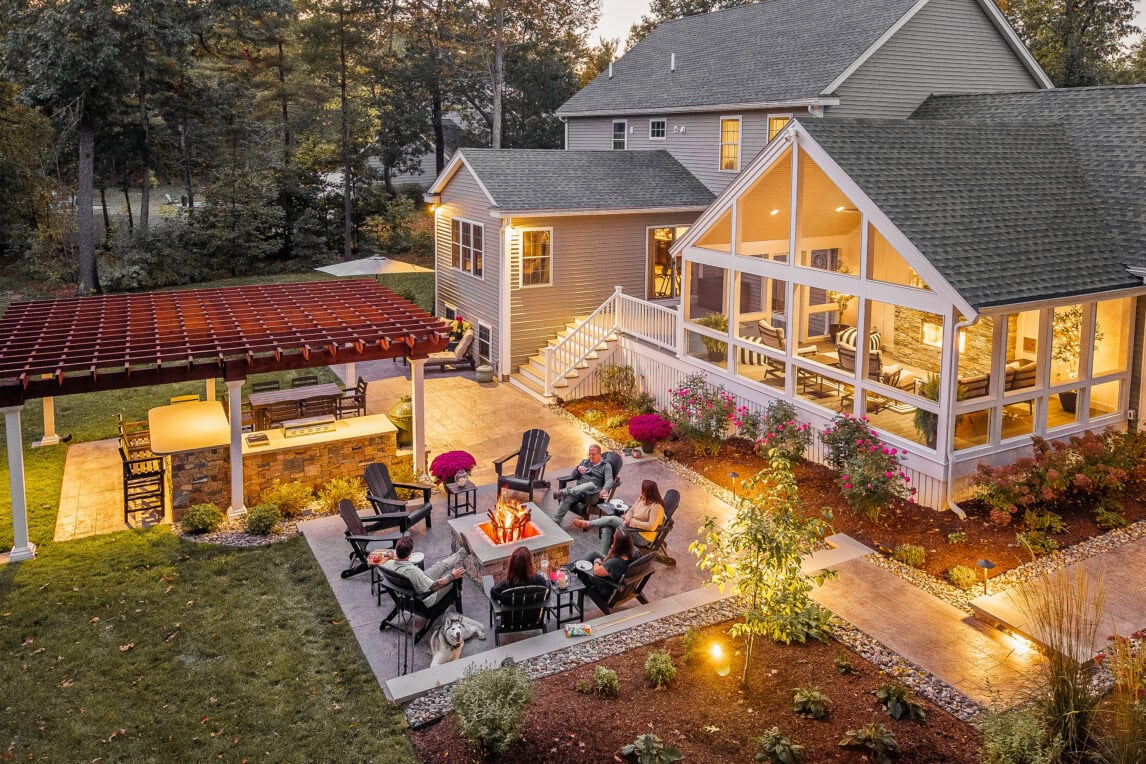 Backyard in Dunstable, MA with fire pit patio, outdoor kitchen, pergola, screened-in porch.