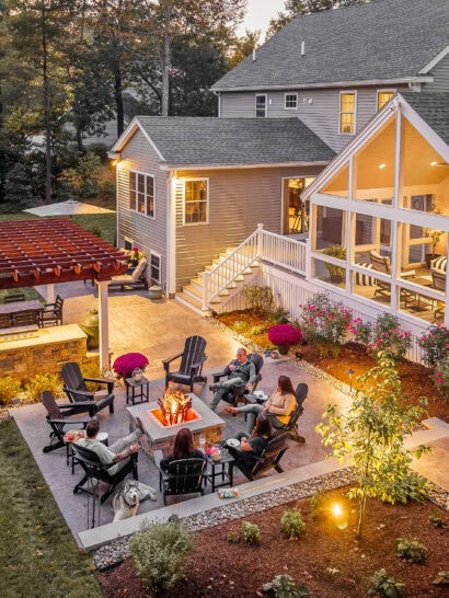 Backyard in Dunstable, MA with fire pit patio, outdoor kitchen, pergola, screened-in porch.