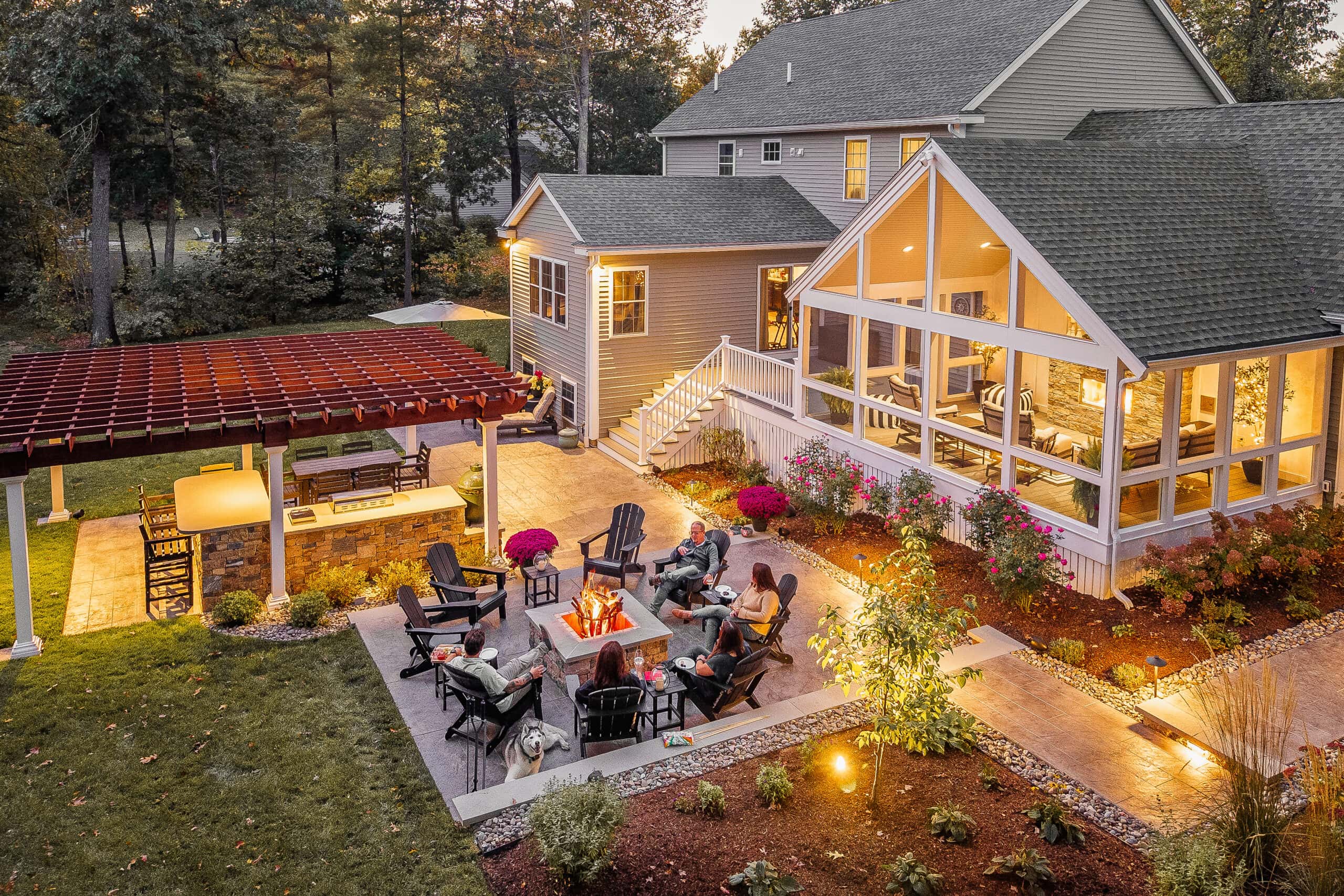 Backyard in Dunstable, MA with fire pit patio, outdoor kitchen, pergola, screened-in porch.