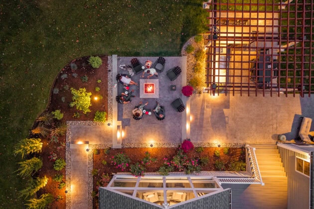 Overhead drone view of backyard in Dunstable, MA with fire pit patio, outdoor kitchen, pergola, screened-in porch.