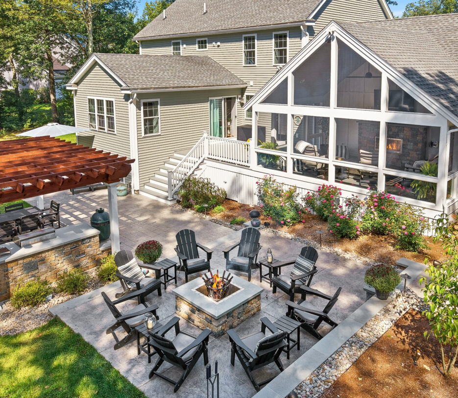 Drone view of Backyard in Dunstable, MA with fire pit patio, outdoor kitchen, pergola, screened-in porch.