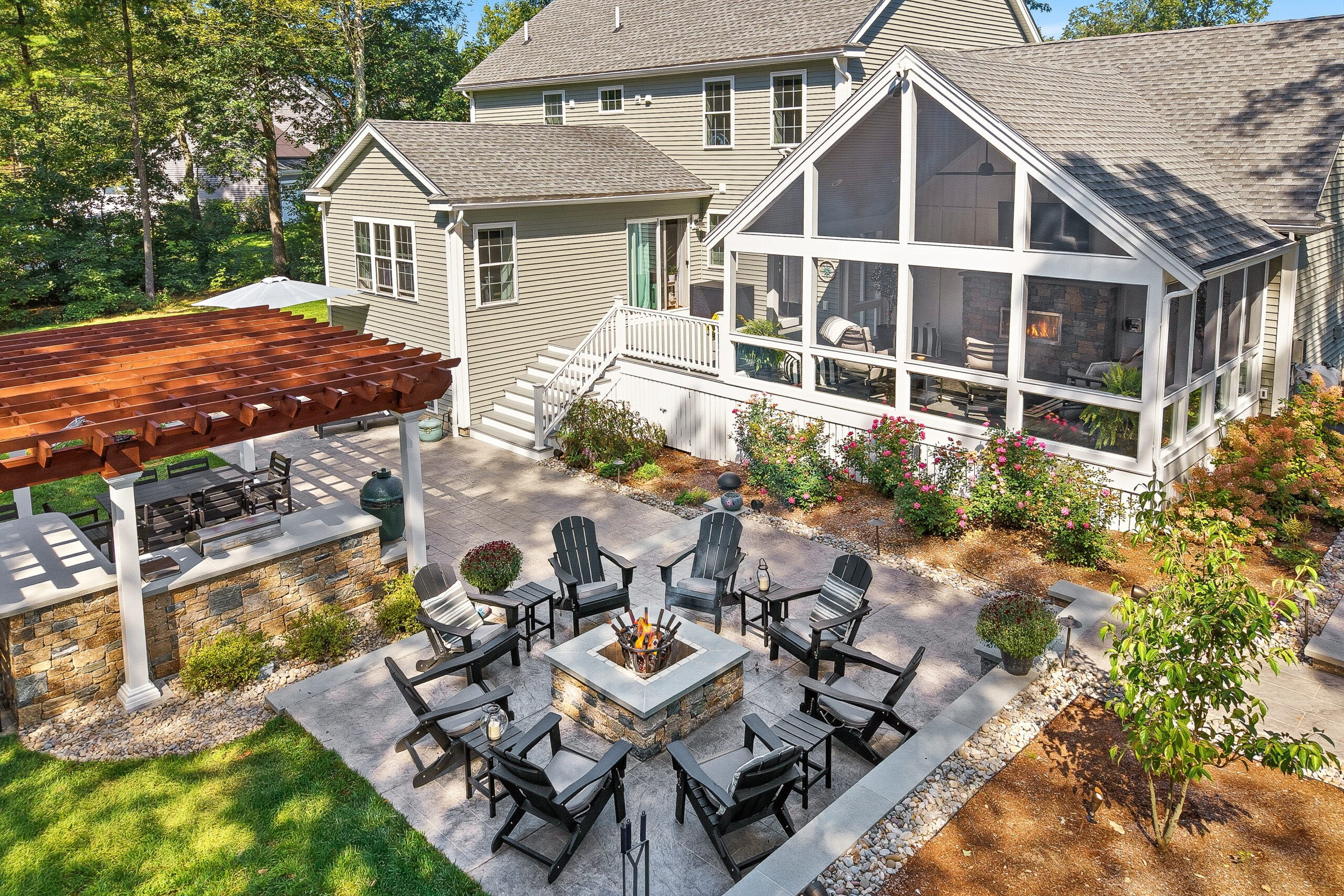 Drone view of Backyard in Dunstable, MA with fire pit patio, outdoor kitchen, pergola, screened-in porch.