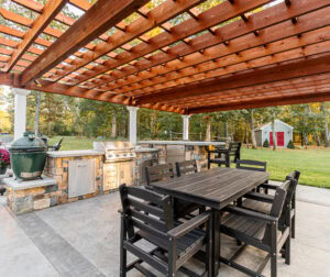Outdoor kitchen and dining area under a pergola in Dunstable, MA