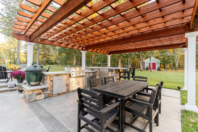 Outdoor kitchen and dining area under a pergola in Dunstable, MA