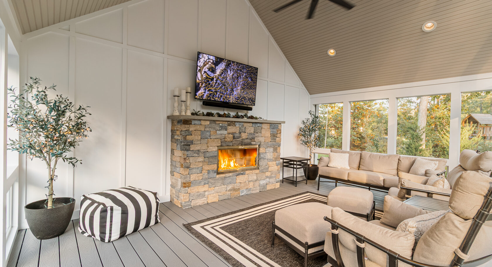 Interior of the three-season, screened-in porch with stone veneer gas fireplace insert. Built with Trex composite decking. Landscape design in Dunstable, MA built by Dex by Terra.