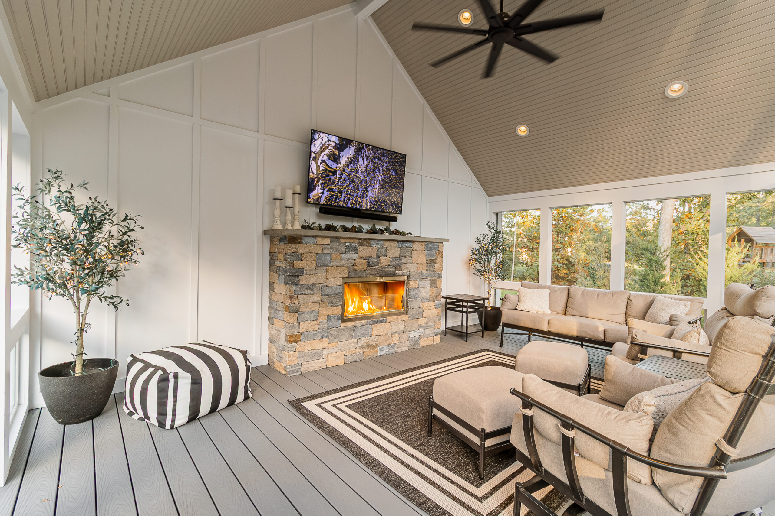 Interior of the three-season, screened-in porch with stone veneer gas fireplace insert. Built with Trex composite decking. Landscape design in Dunstable, MA built by Dex by Terra.