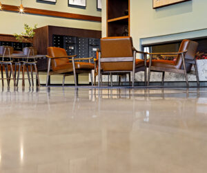 A polished concrete floor with chairs and gas fireplace in the main lobby area of 75 Canal Apartments in Manchester, NH.