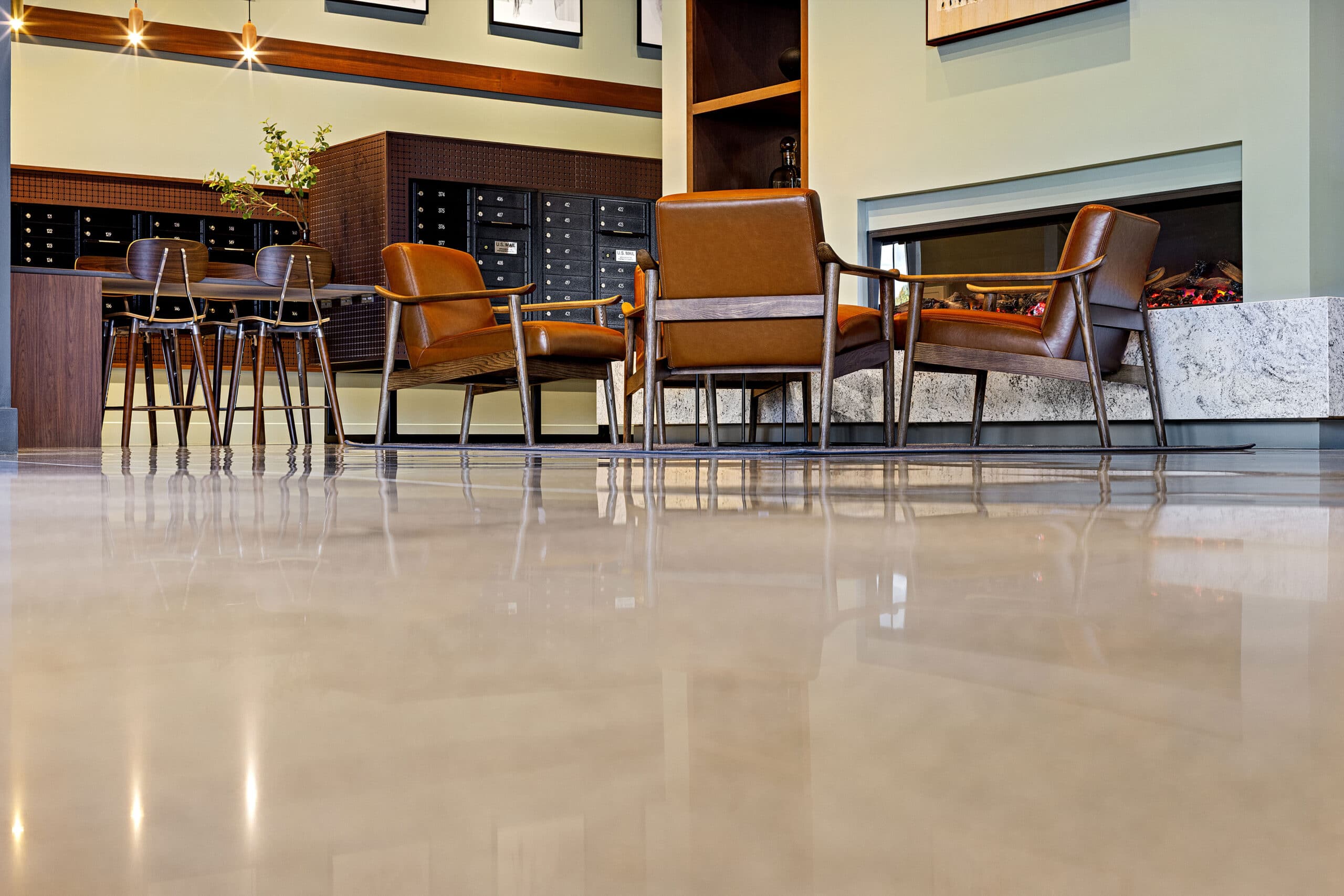 A polished concrete floor with chairs and gas fireplace in the main lobby area of 75 Canal Apartments in Manchester, NH.