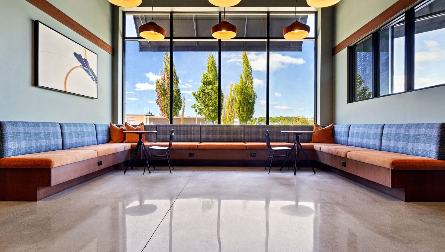 A polished concrete floor with seating areas by a window in the main lobby area of 75 Canal Apartments in Manchester, NH.