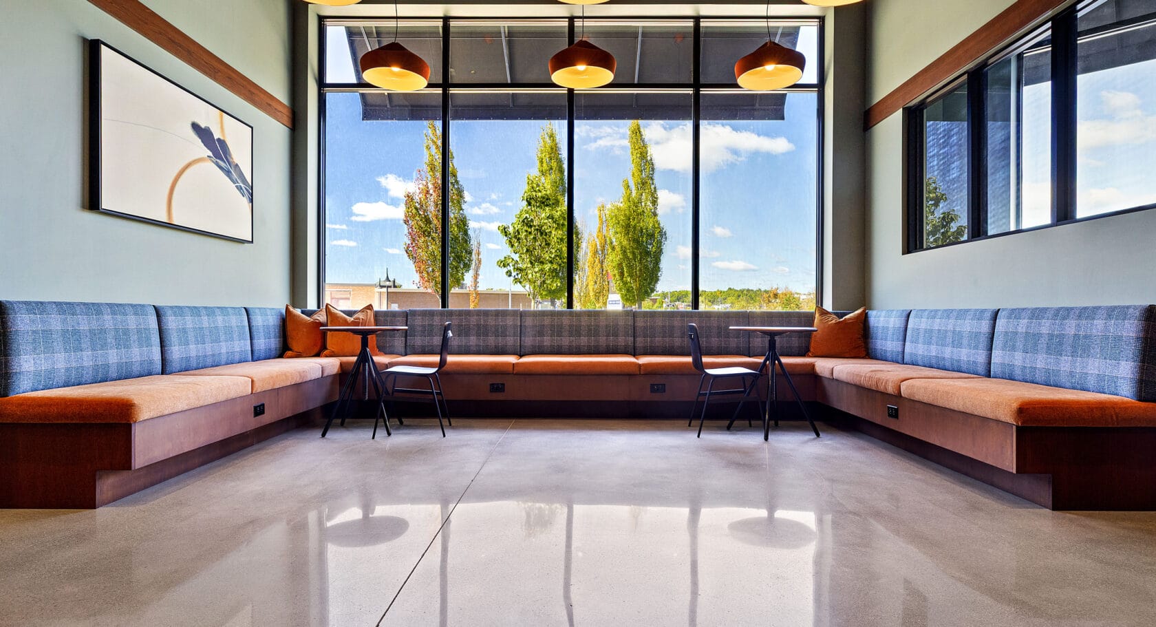 A polished concrete floor with seating areas by a window in the main lobby area of 75 Canal Apartments in Manchester, NH.