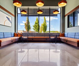 A polished concrete floor with seating areas by a window in the main lobby area of 75 Canal Apartments in Manchester, NH.