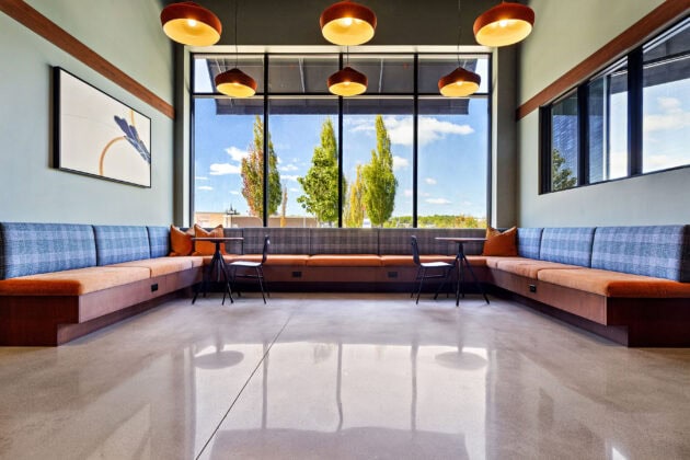 A polished concrete floor with seating areas by a window in the main lobby area of 75 Canal Apartments in Manchester, NH.