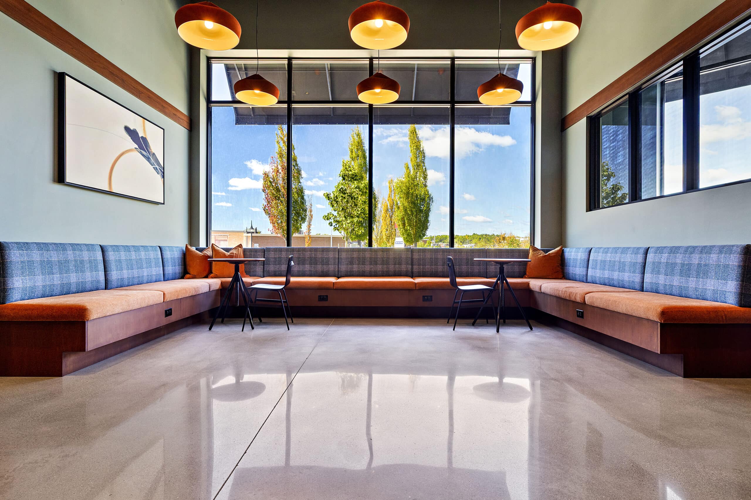 A polished concrete floor with seating areas by a window in the main lobby area of 75 Canal Apartments in Manchester, NH.