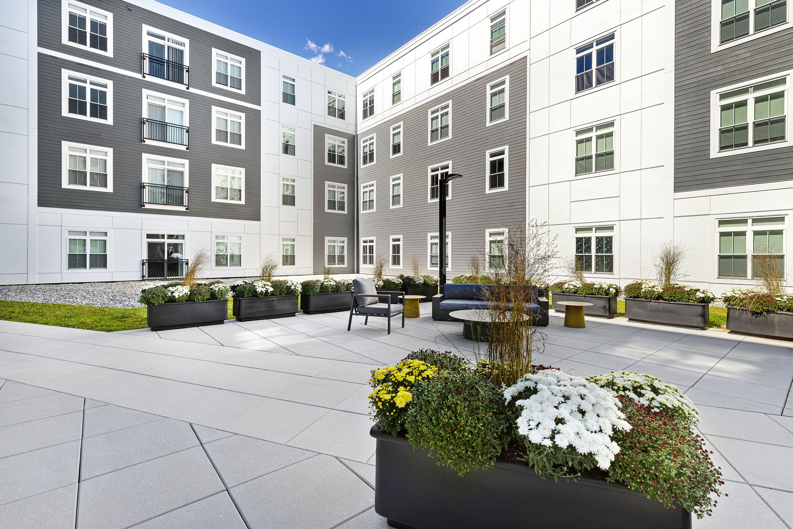 The smaller second floor courtyard area with seating and planters at 75 Canal Apartments in Manchester, NH. Hardscaping and landscaping by Dex by Terra of Hudson, MA.