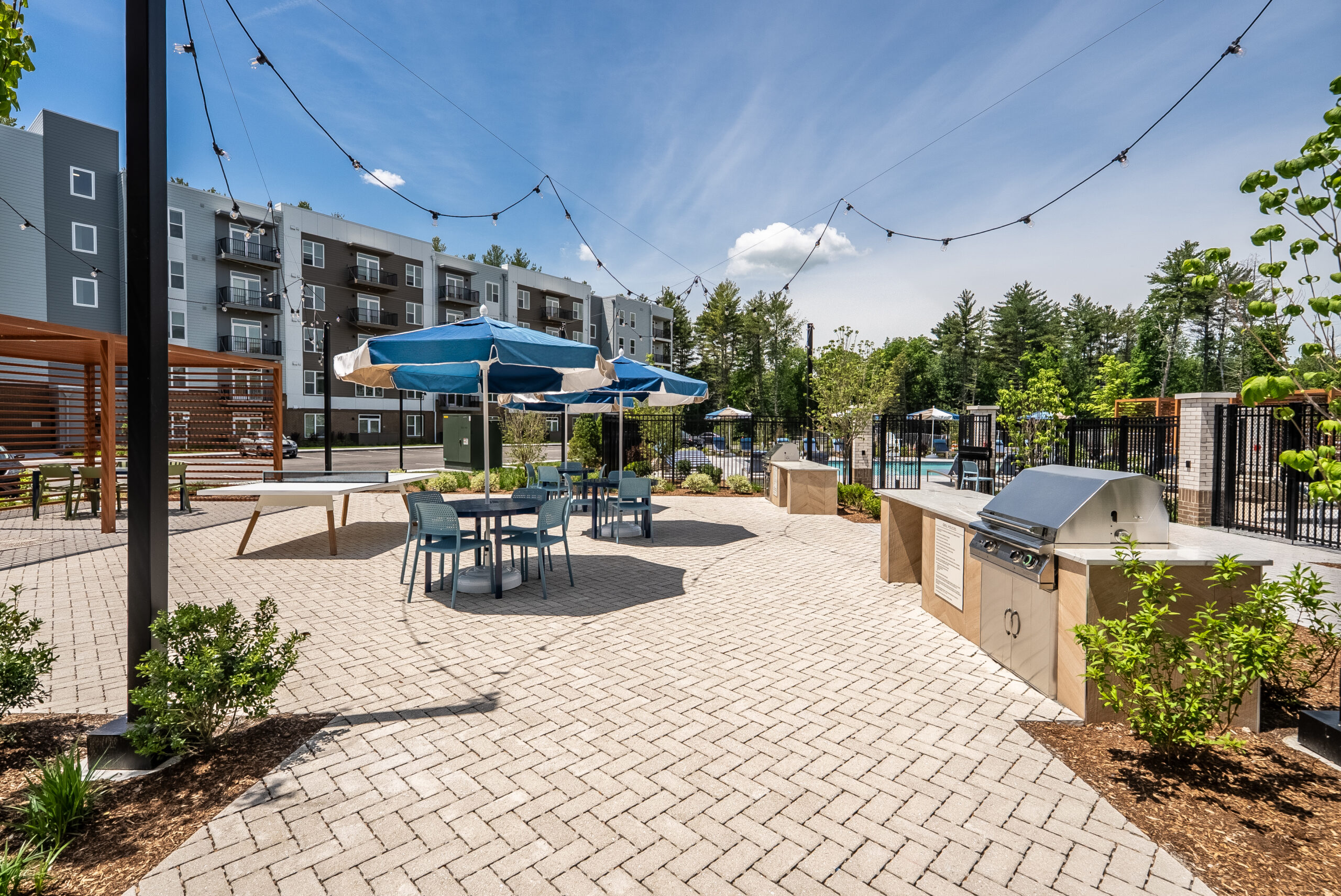 A a paver courtyard for grilling and dining at The Penstone Apartments in Walpole, MA. Hardscaping and landscaping by Dex by Terra of Hudson, MA.