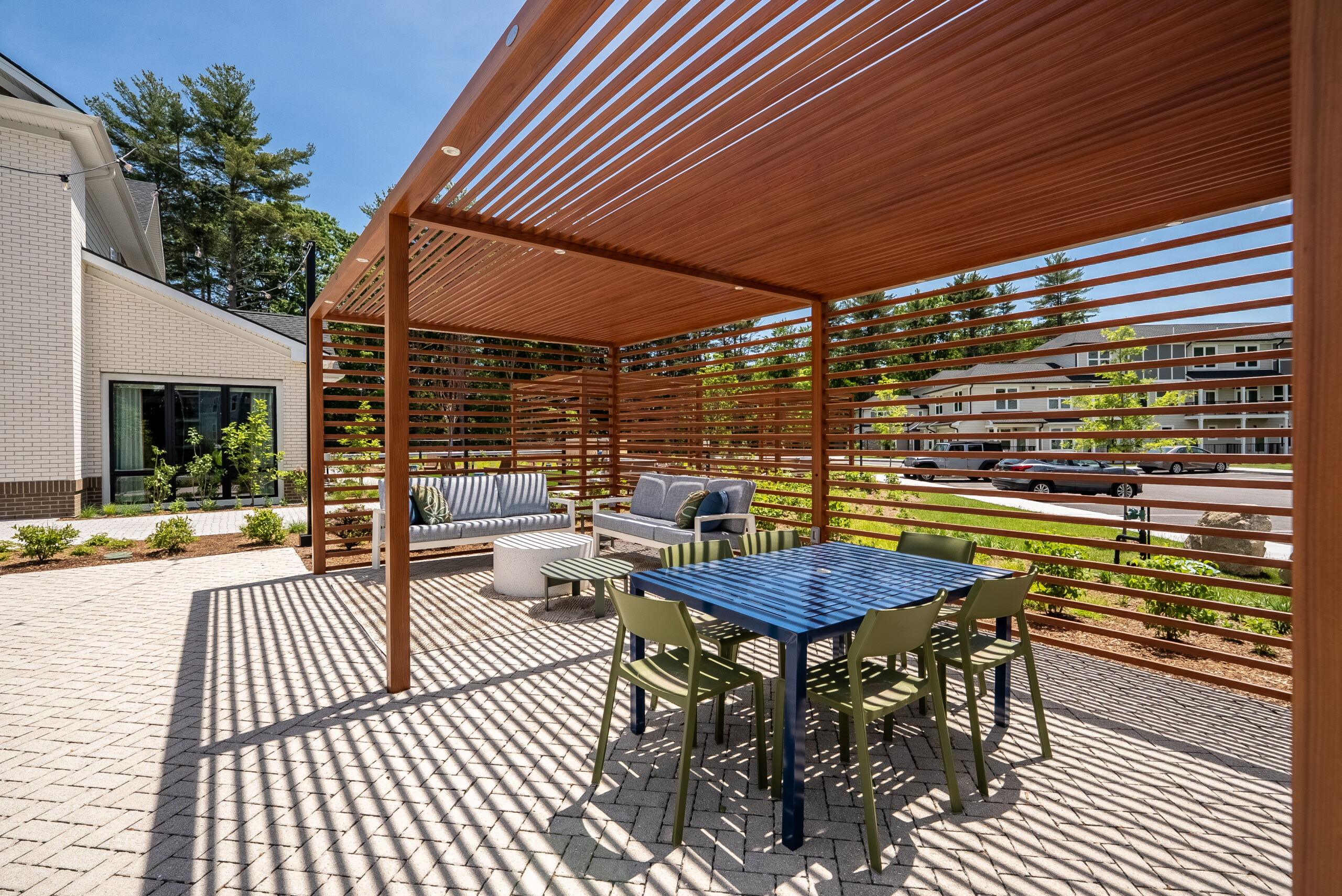 Modern pergolas provide shade for dining and lounge areas at The Penstone Apartments in Walpole, MA. Hardscaping and landscaping by Dex by Terra of Hudson, MA.