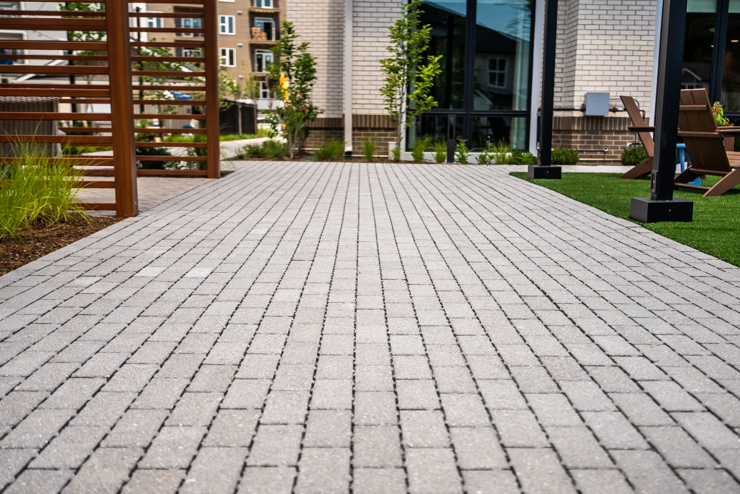 Brick paver walkways connect the clubhouse to the pool and other amenity areas at The Penstone Apartments in Walpole, MA. Hardscaping and landscaping by Dex by Terra of Hudson, MA.