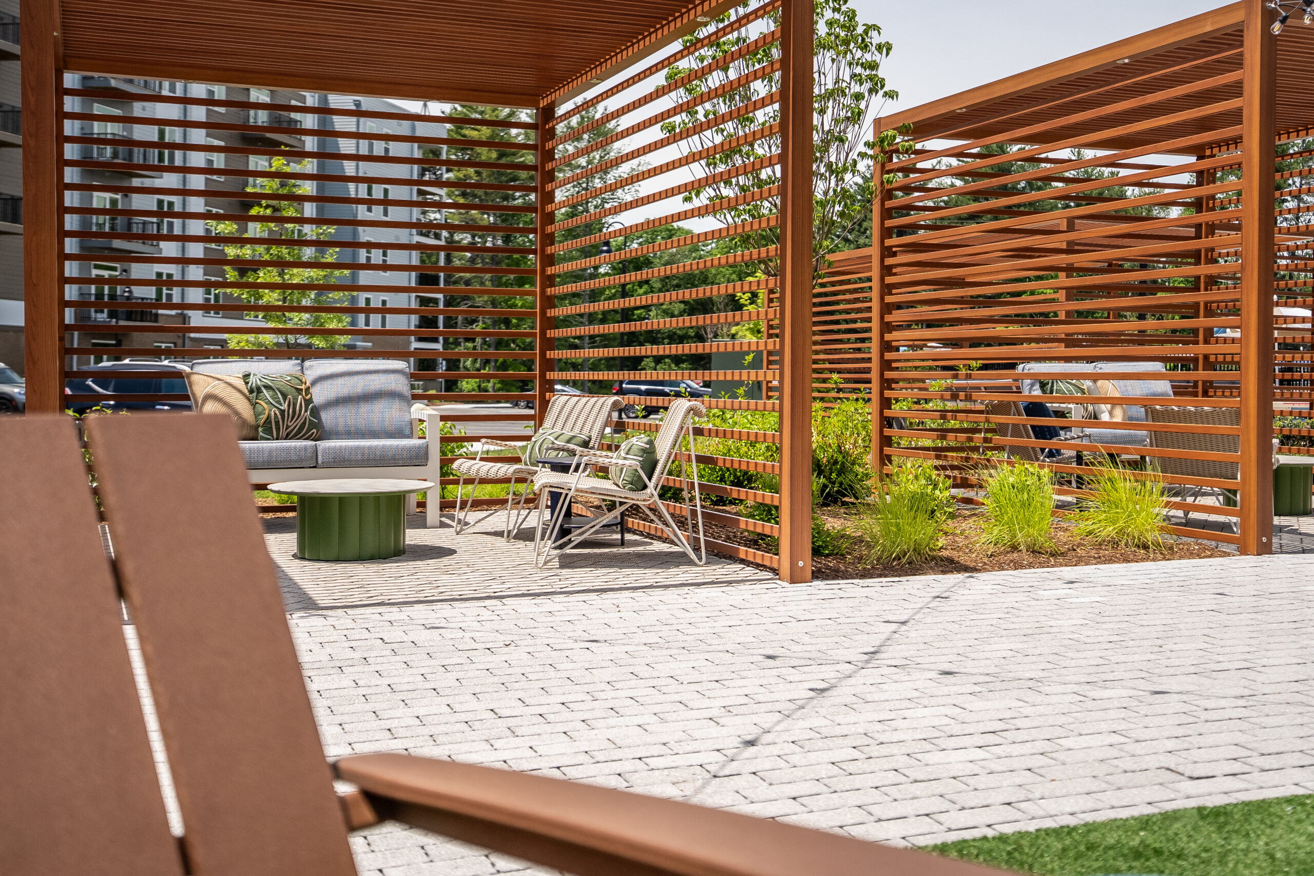 Lounge areas with shade provided by pergolas and landscaping at The Penstone Apartments in Walpole, MA. Hardscaping and landscaping by Dex by Terra of Hudson, MA.