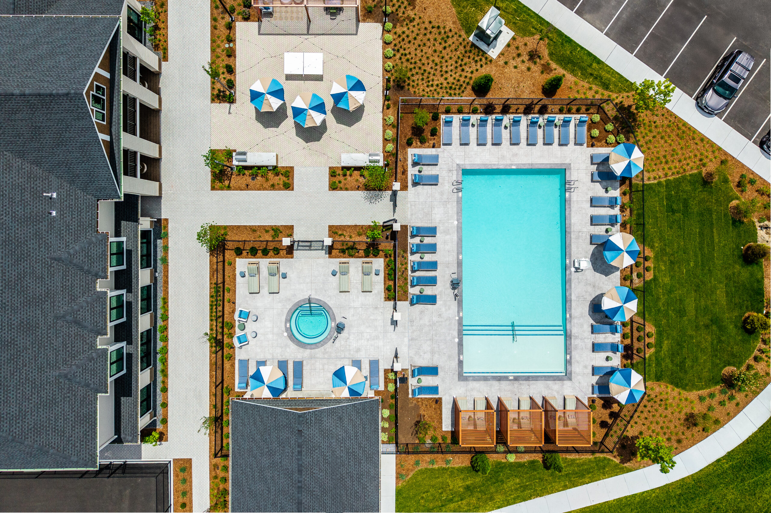 Drone view of the amenity areas with pool, pergolas, spa, and grill zone. The Penstone Apartments in Walpole, MA. Hardscaping and landscaping by Dex by Terra of Hudson, MA.